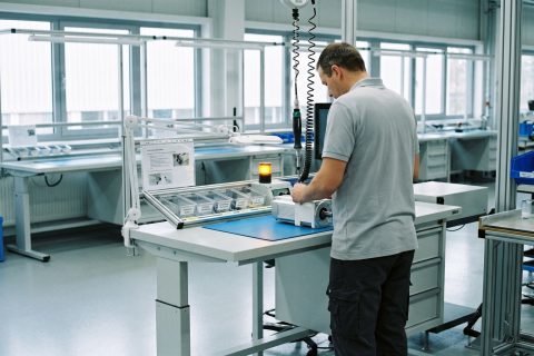 Techniker montiert an einem hellen Montagearbeitsplatz eine kompakte Antriebseinheit.